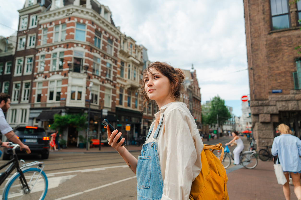 Woman using smartphone while exploring Amsterdam - Journey House Travel
